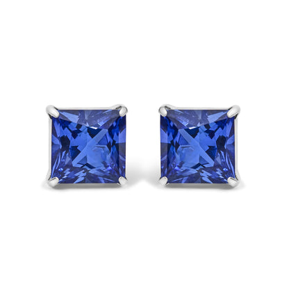 Pair of white metal earrings shown from the front with square-shaped blue gemstones in four-prong settings.