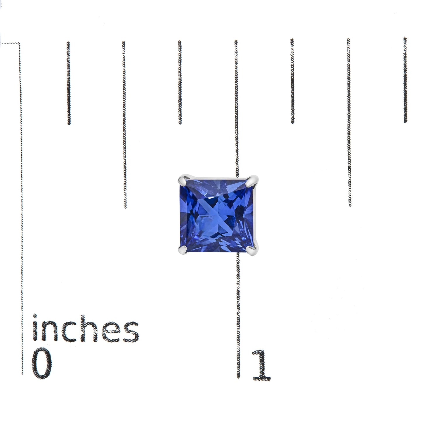 Close-up front view of a single white metal earring featuring a princess-shaped blue gemstone in a four-prong setting, shown on a measurement scale.