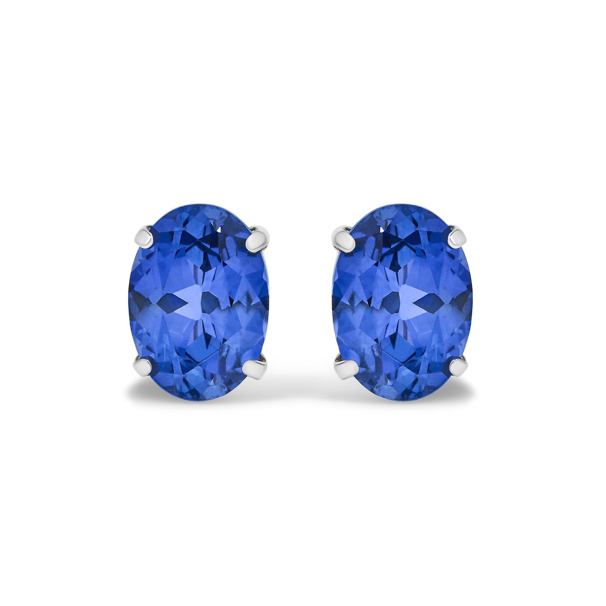 Close-up front view of white metal earrings, each featuring an oval blue gemstone in a four-prong setting.