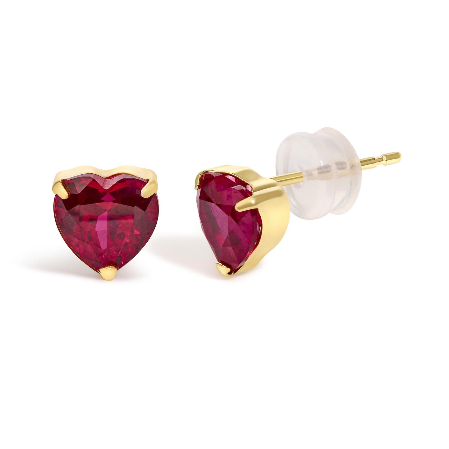 Close-up front and side angle of a pair of yellow metal stud earrings, each featuring a heart-shaped red gemstone in a three-prong setting, shown on a white background.