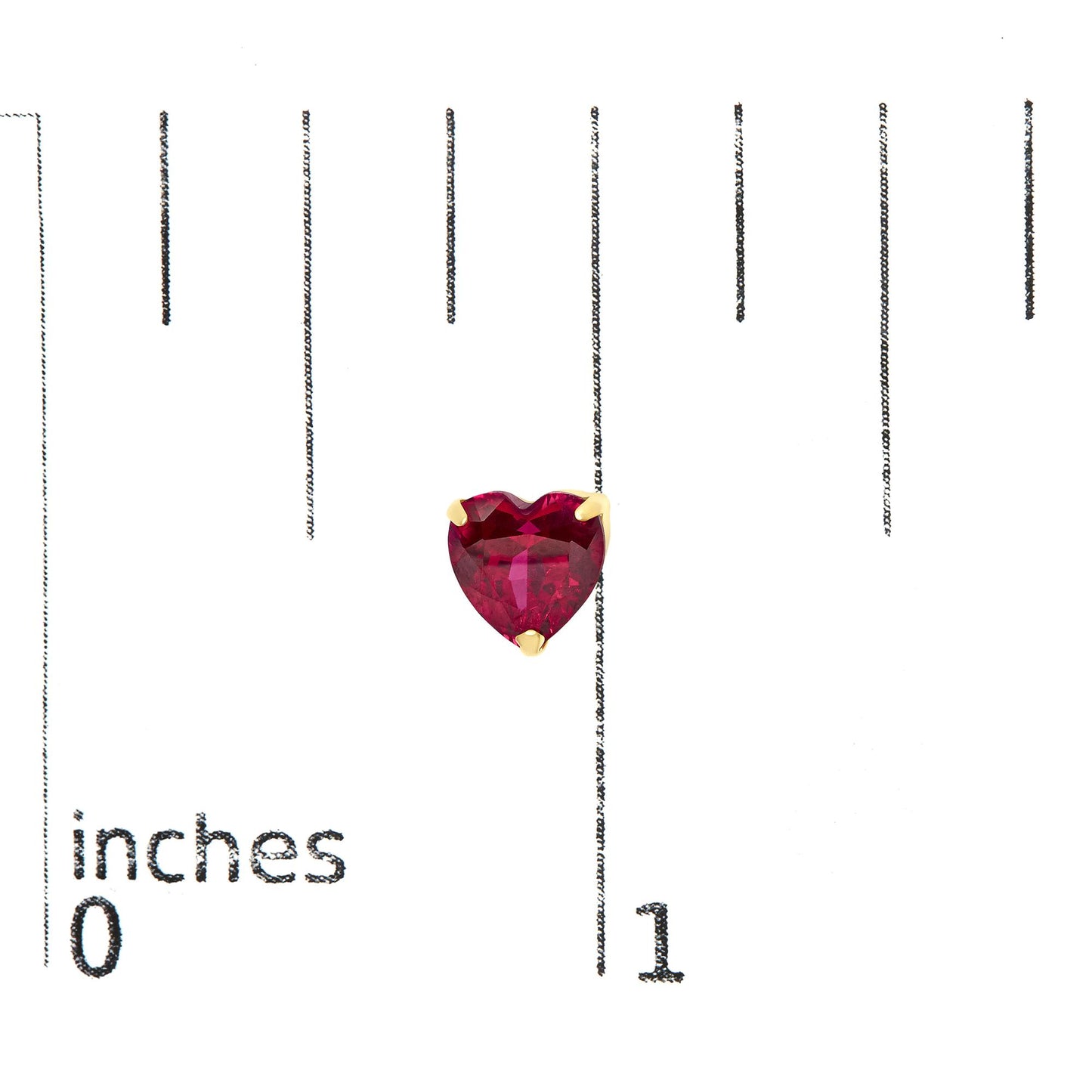 Close-up front view of yellow metal heart-shaped red gemstone stud earrings shown on a ruler scale.