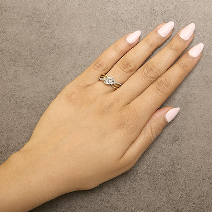 Ring with intertwined yellow and white metal bands, featuring round white gemstones in prong settings, shown worn on a model's finger from a top angle.