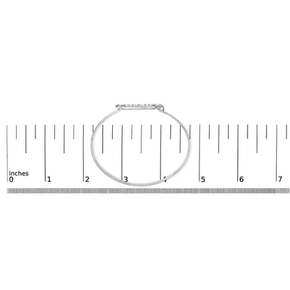 White metal bracelet with a horizontal oval centerpiece set with round white gemstones in prong settings, shown flat on a ruler for scale, photographed from above.