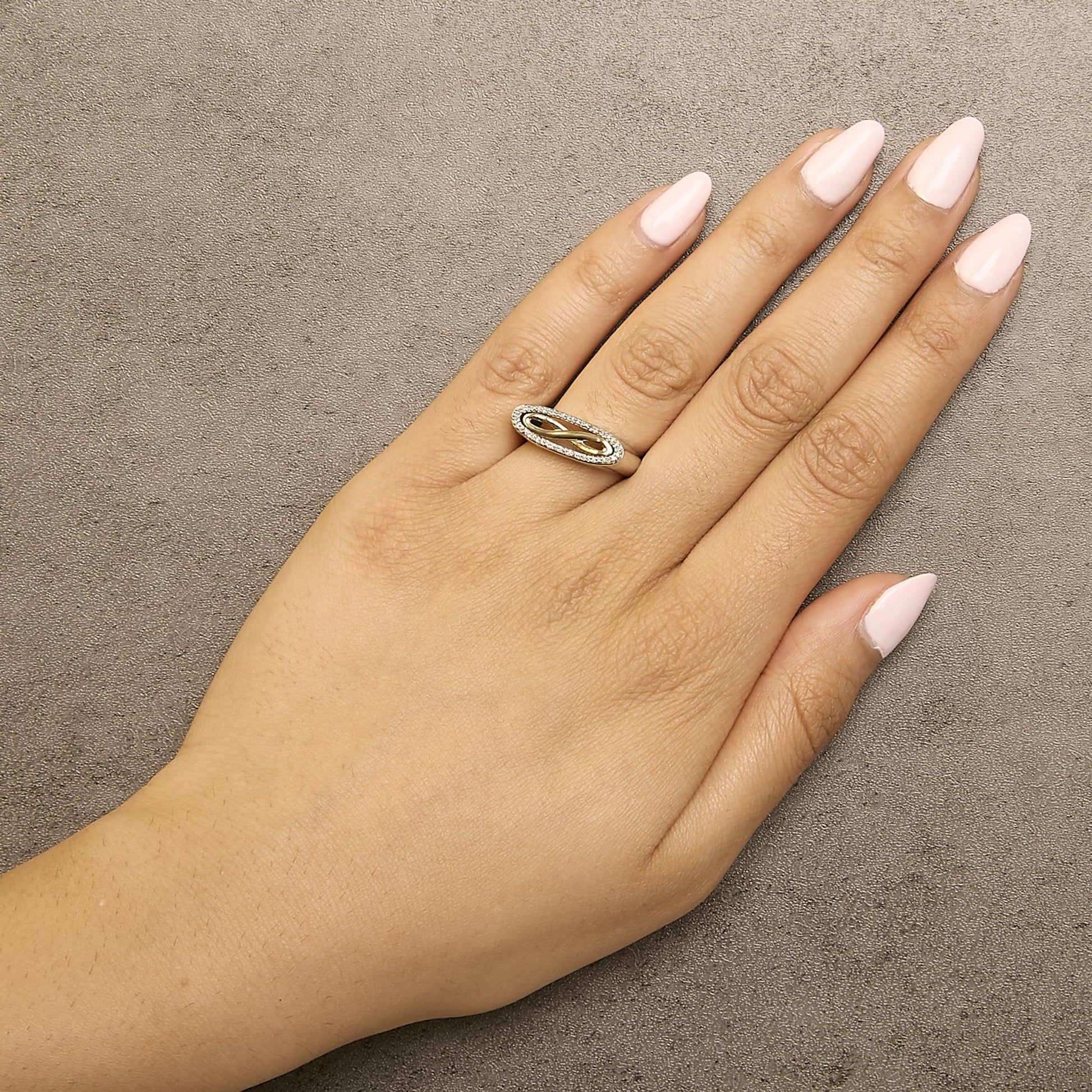 Ring with yellow and white metal colors featuring a twisted design and round white gemstones in a shared prong setting, shown worn on a model's hand from a top angle.