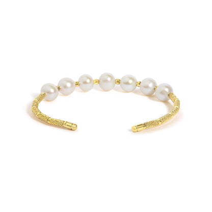 Close-up front angle of a yellow metal bracelet featuring a textured band and large white gemstones evenly spaced along the top.