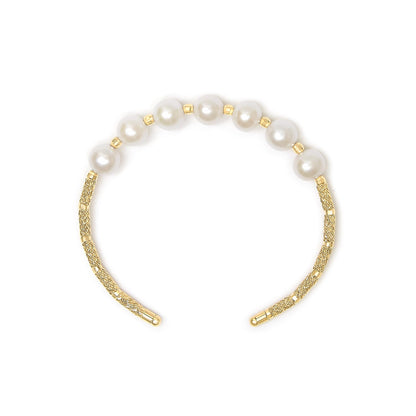 Close-up front view of a yellow metal bracelet featuring smooth round white gemstones spaced evenly along textured segments.