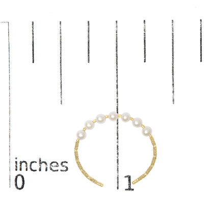 Yellow metal bracelet with pearl-like white gemstones strung along top half, shown on a scale, angled flat overhead.