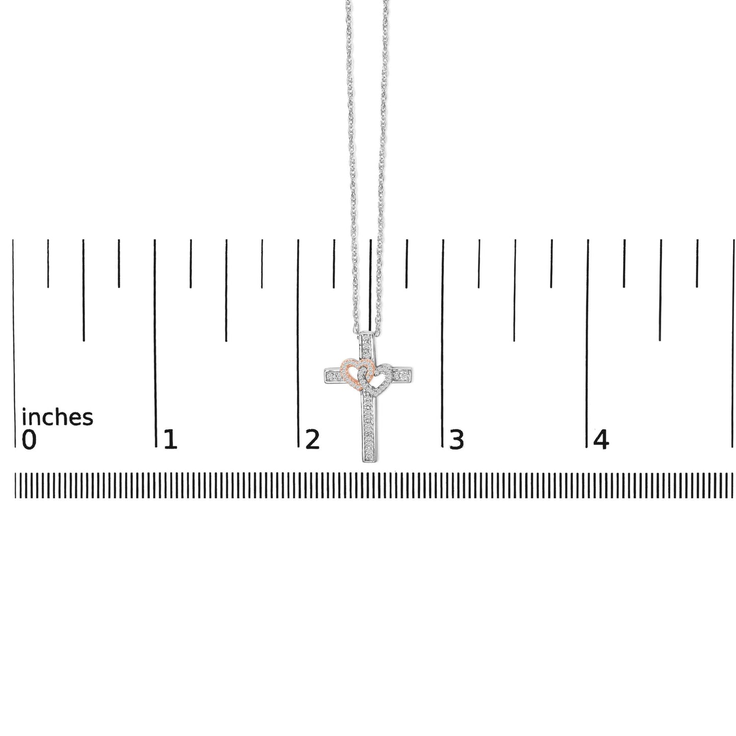 Necklace shown on a scale, featuring a cross pendant with two overlapping hearts; the cross and one heart are white metal with white gemstones in a pave setting, and the other heart is rose metal with white gemstones, front view.