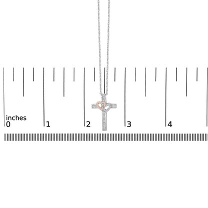 Necklace shown on a scale, featuring a cross pendant with two overlapping hearts; the cross and one heart are white metal with white gemstones in a pave setting, and the other heart is rose metal with white gemstones, front view.