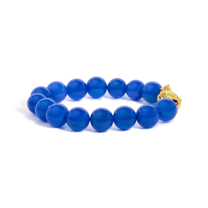 Close-up front angle of a yellow metal bracelet featuring round blue gemstone beads in drilled settings.