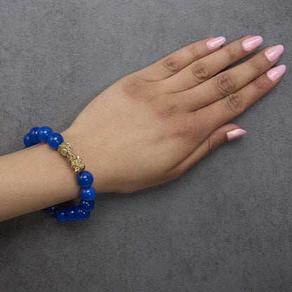 Yellow metal bracelet with round blue gemstones and decorative accents, shown worn on model's wrist from an angled top view.
