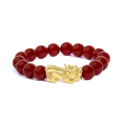 Close-up image of a yellow metal bracelet with round red gemstone beads and an ornate dragon-shaped clasp, shown on a white background from a side angle.
