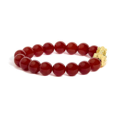Yellow metal bracelet with round red gemstone beads in a drilled setting, shown in a close-up shot on a white background.