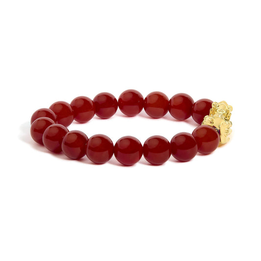 Yellow metal bracelet with round red gemstone beads in a drilled setting, shown in a close-up shot on a white background.