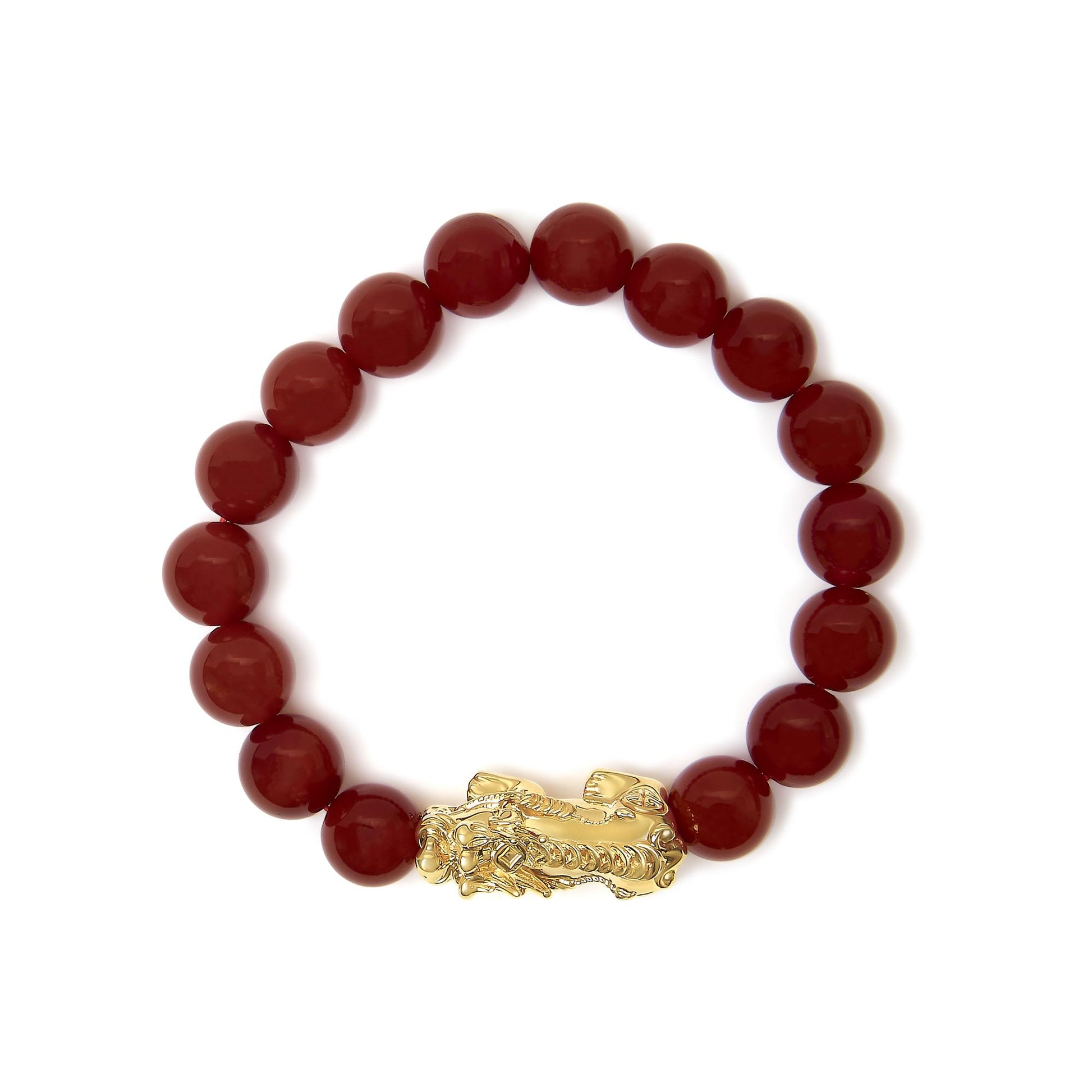 Close-up top view of a yellow metal bracelet with round red gemstone beads and an ornate clasp.