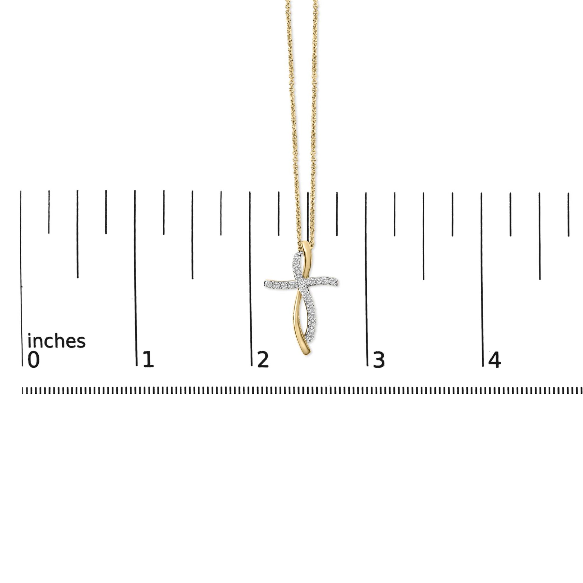Necklace with a cross-shaped pendant featuring intertwined yellow and white metal strands, white round gemstones in prong setting on the white metal strand, shown hanging on a ruler scale, front view.