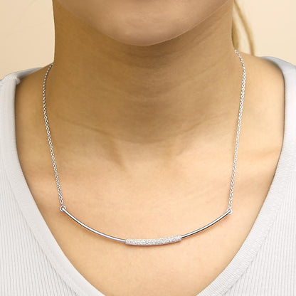 Close-up front view of a white metal necklace shown worn on a model, featuring a curved bar with a section of small white gemstones set in a pave style.