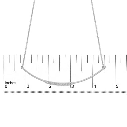 White necklace with a curved bar pendant set with small white gemstones in a pave setting, shown on a ruler for scale, front-facing angle.