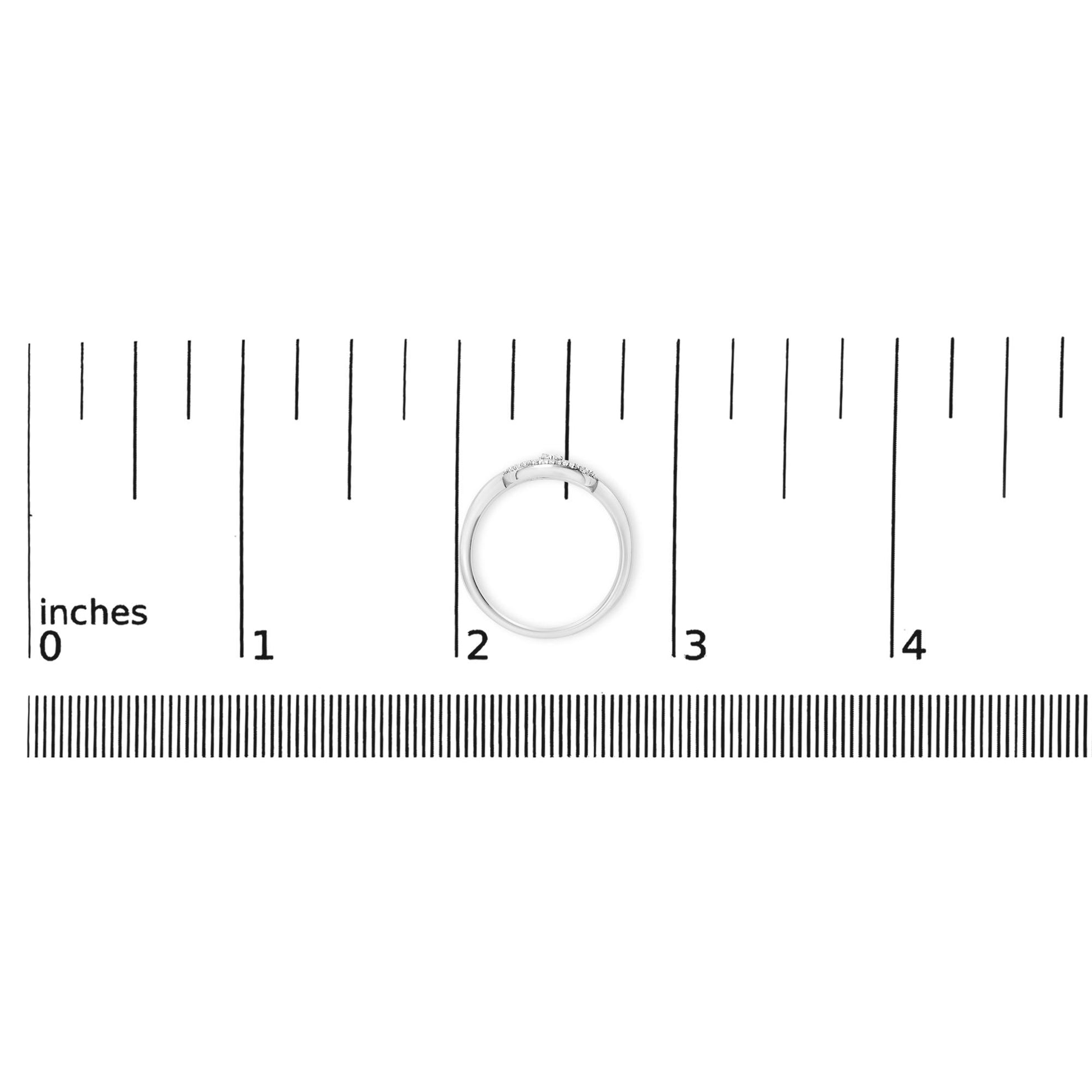 Image of a two-tone ring with a single round white gemstone in a three-prong setting and multiple round white gemstones in a shared prong setting, shown on a ruler scale from a top-down angle.