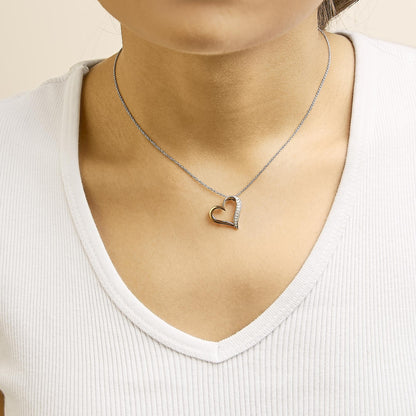 Necklace shown worn on a model, featuring a heart-shaped pendant with white and rose metal colors, adorned with white round pave-set gemstones on one side, shot from the front.