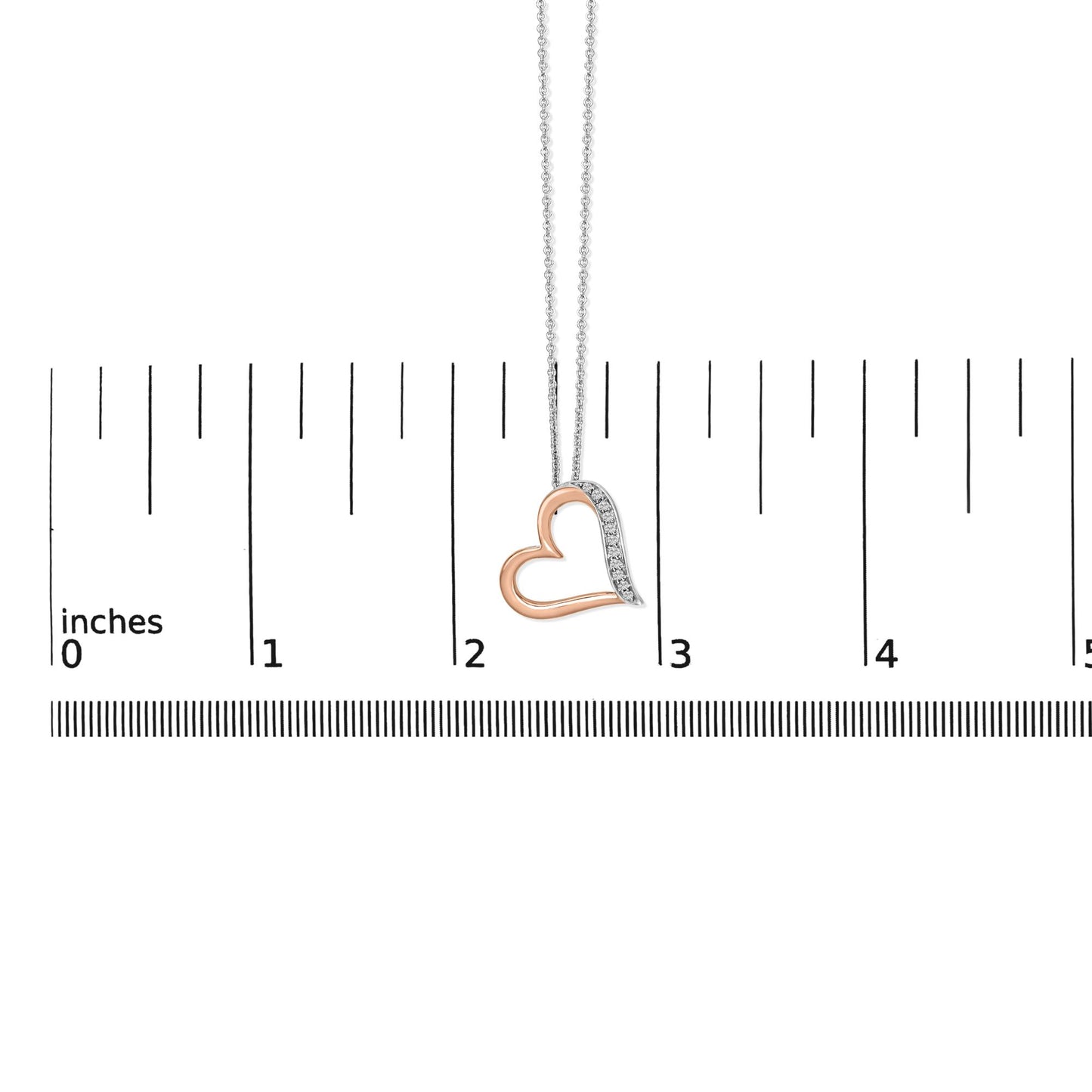 Close-up front view of a heart-shaped necklace pendant in white and rose metal colors, with one side featuring white round pave-set gemstones, shown hanging on a measuring scale.