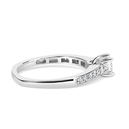Side angle view of a white metal ring featuring a princess-shaped gemstone in a four-prong setting and multiple round gemstones in a shared prong setting along the band.