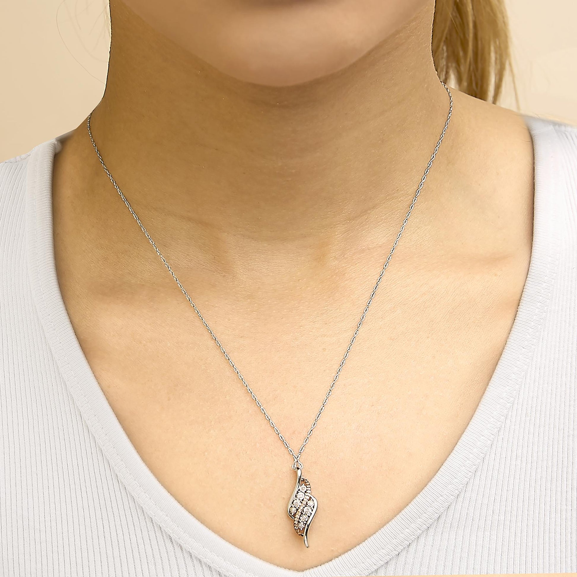 Necklace shown worn on a model, featuring a pendant with an elegant twisted design in white and rose metal colors, adorned with round white gemstones in prong settings; front-facing close-up shot.