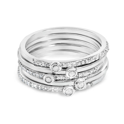 Close-up front angle of stacked white metal rings, each adorned with small white gemstones in prong settings and round white gemstones in bezel settings.