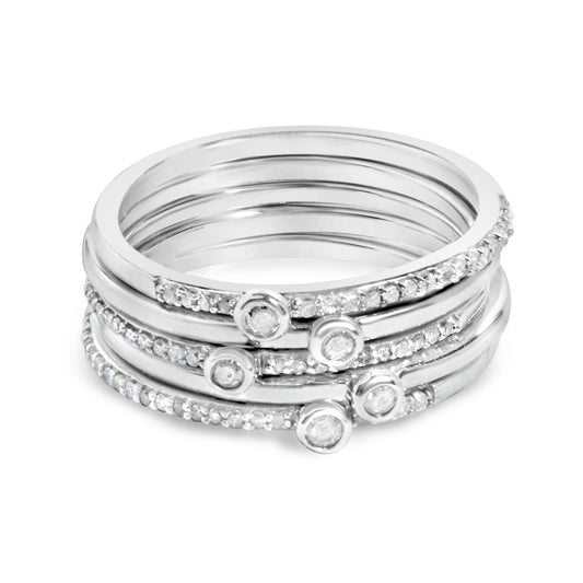 Close-up front angle of stacked white metal rings, each adorned with small white gemstones in prong settings and round white gemstones in bezel settings.