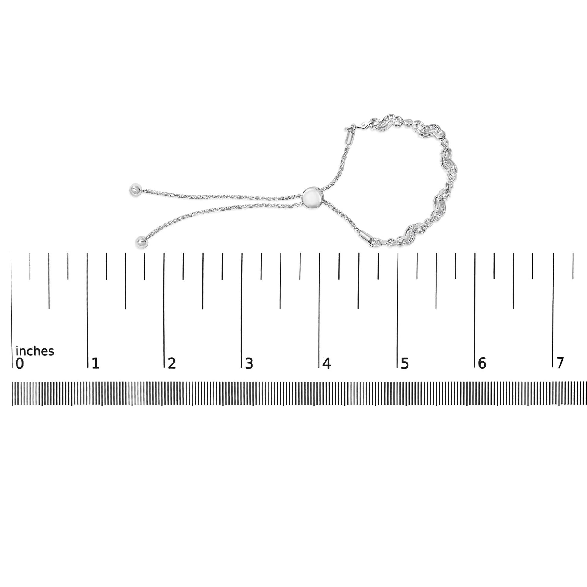 White metal bracelet with round white gemstones in prong settings, featuring a chain and adjustable sliding clasp, shown on a scale from a top view.