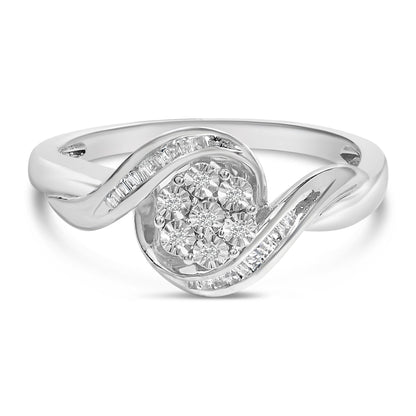 Close-up front angle of a white metal ring featuring a swirl design with channel-set white baguette-shaped gemstones on the curves and a cluster of round prong-set white gemstones in the center.