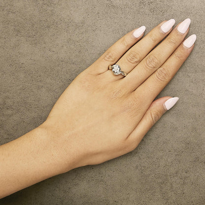 White metal ring with a round white gemstone in a prong setting and baguette-shaped white gemstones in a channel setting, shown worn on a model's finger from a top angle.
