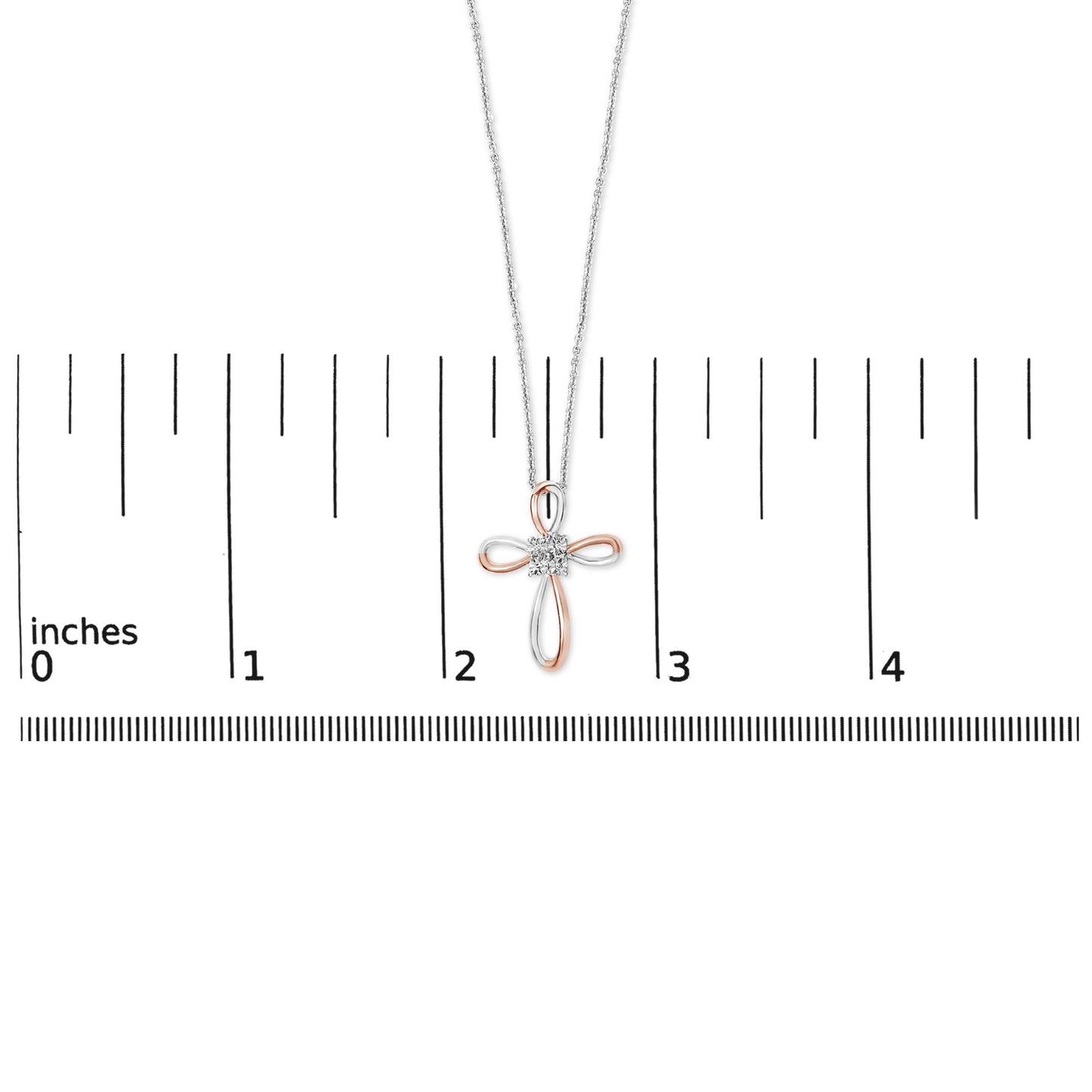 Necklace shown on a scale, featuring a cross-shaped pendant with white and rose metal loops and four round white gemstones in bezel settings, shot from the front.