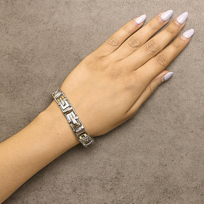 Bracelet with geometric links in yellow and white metal and white pave-set round gemstones, shown worn on a model’s wrist from a top angle.