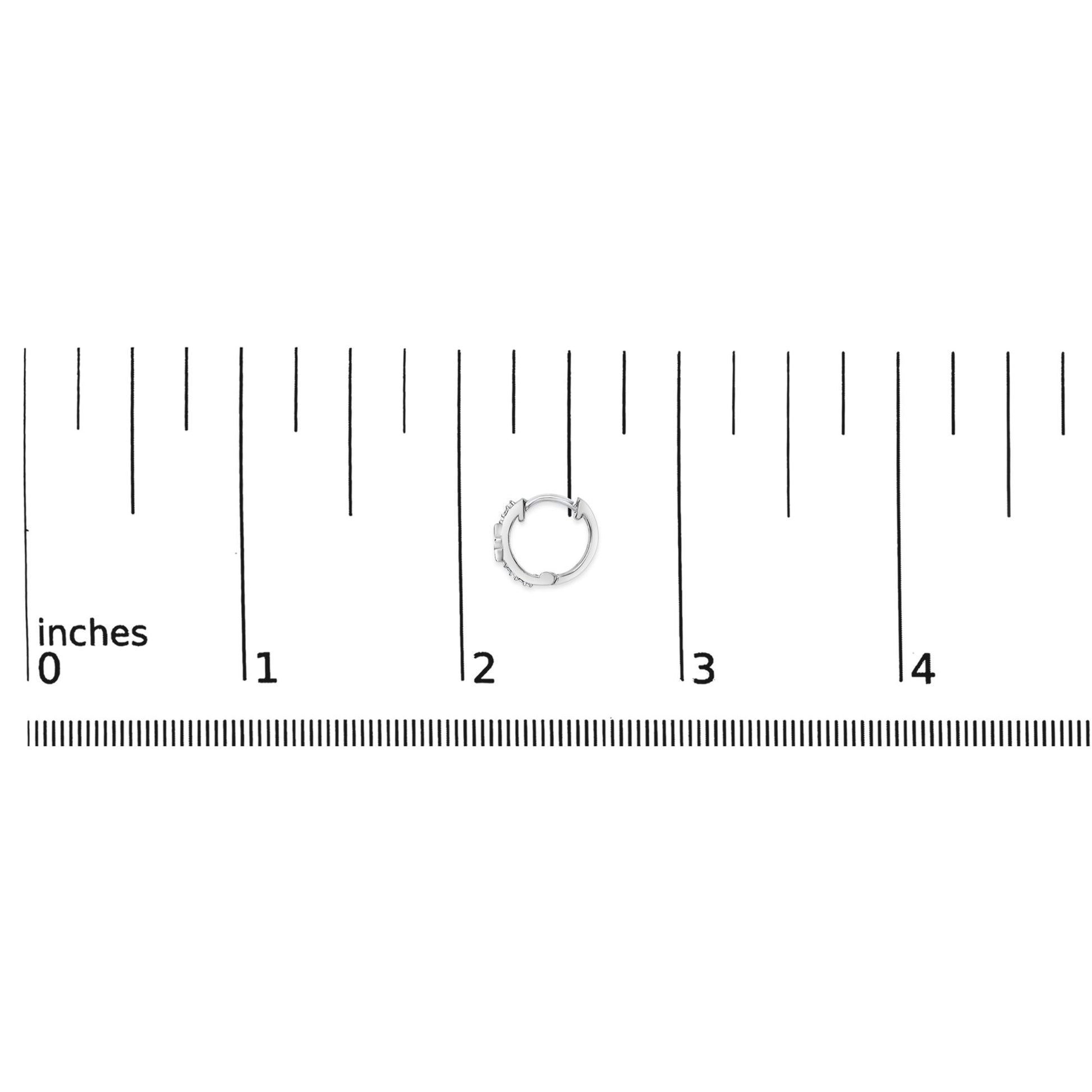 Close-up image of a small white-colored hoop earring with round white gemstones in pave setting, shown on a ruler scale from a top-down angle.