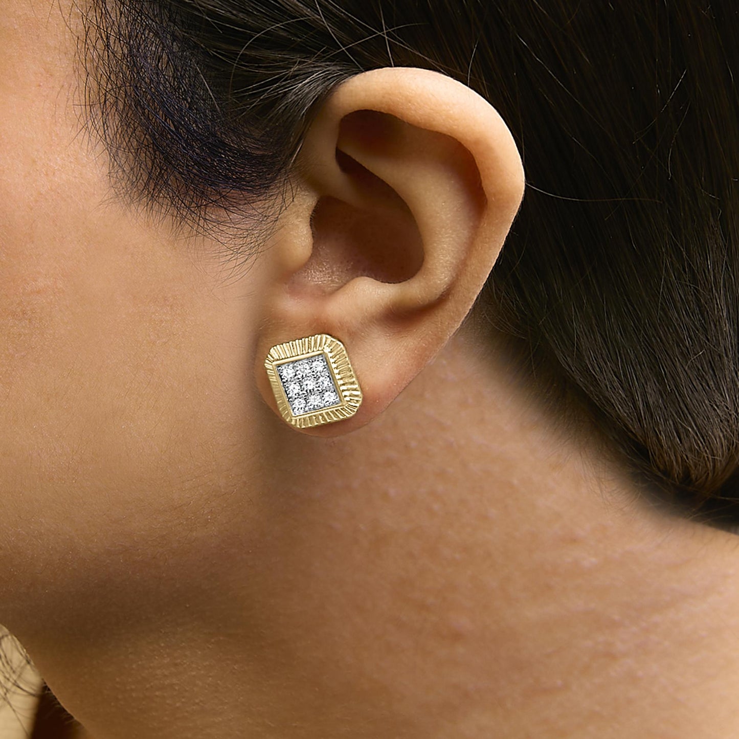 Close-up side view of a model wearing square-shaped earrings with a yellow metal frame and a cluster of round white gemstones set in bezel style at the center in white metal.