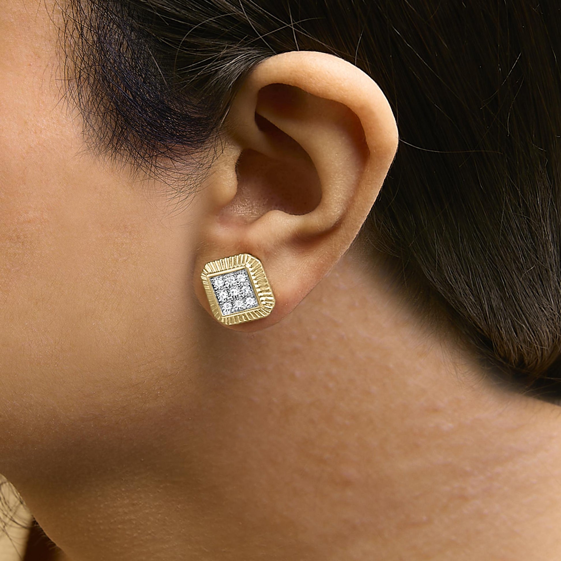 Close-up side view of a model wearing square-shaped earrings with a yellow metal frame and a cluster of round white gemstones set in bezel style at the center in white metal.