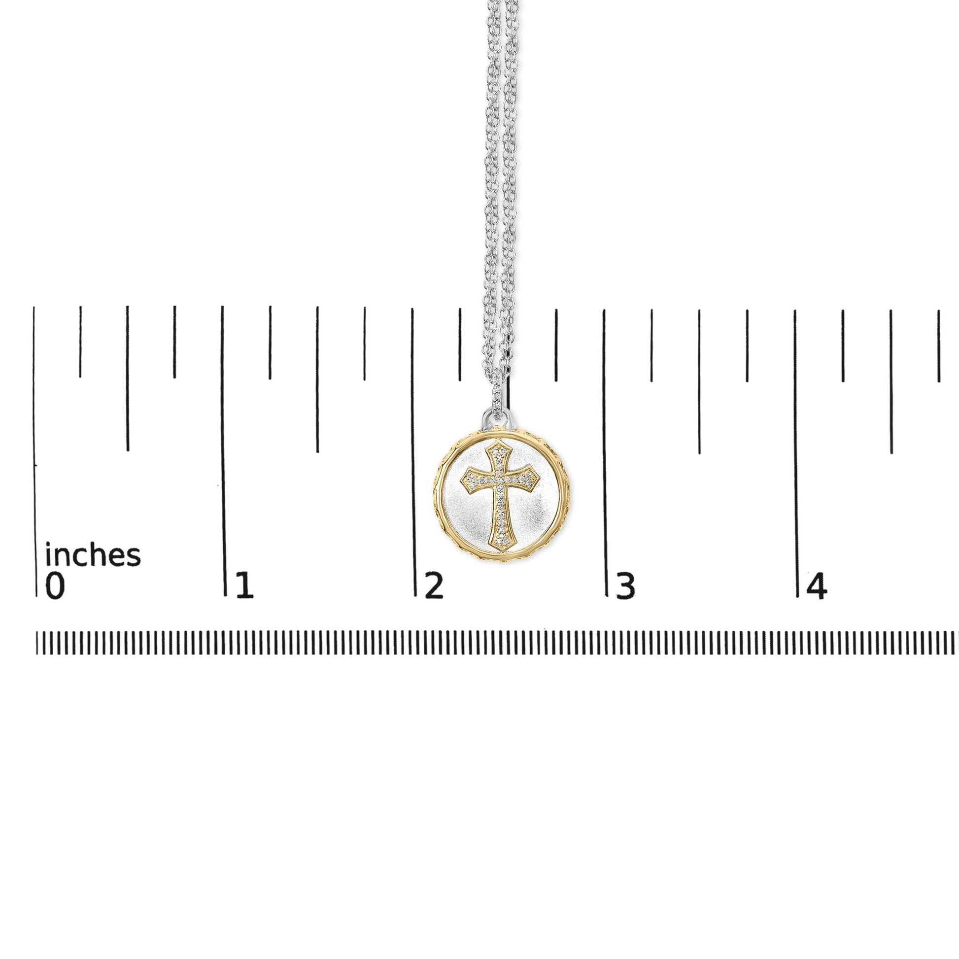 Necklace with round pendant featuring a cross design set with white gemstones in pave setting, surrounded by a yellow border, shown hanging on a scale from a top-front angle.
