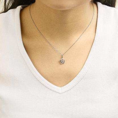 Necklace with a white metal chain and a flower-shaped pendant adorned with round white gemstones shown worn on a model, front-facing angle.