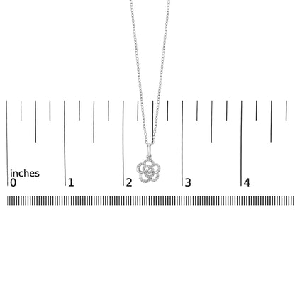 Close-up front view of a white necklace with a flower-shaped pendant, adorned with round white gemstones in a prong setting, shown on a scale.