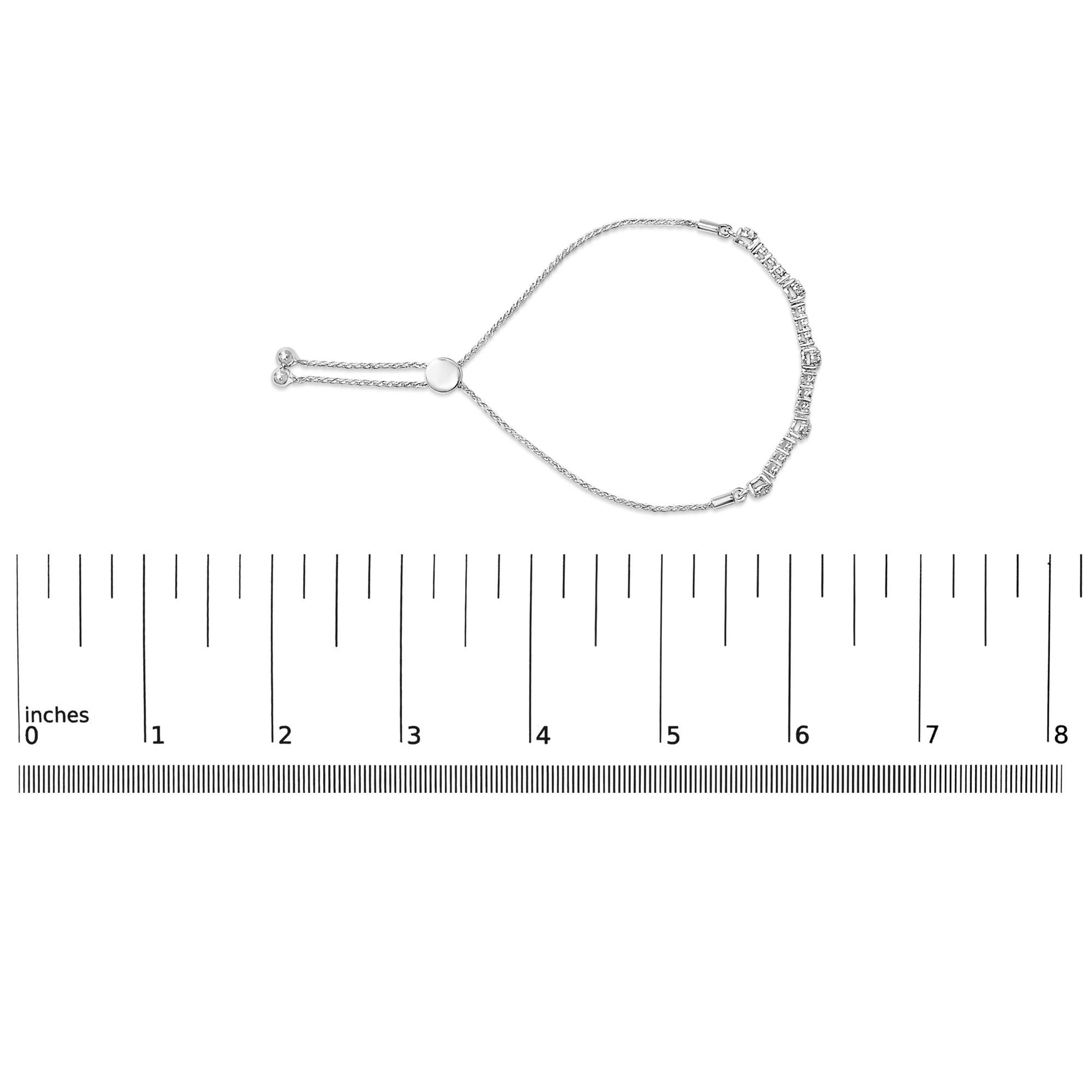 White bracelet with round white gemstones in prong settings along one side, shown flat on a scale, photographed from above.