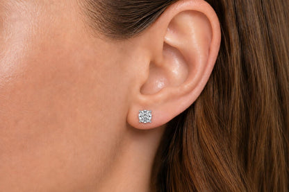 Close-up side view of a model wearing a white metal earring with a round white gemstone in a four-prong setting.