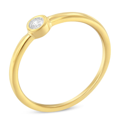 Close-up angle of a yellow metal ring with a single round white gemstone in a bezel setting.