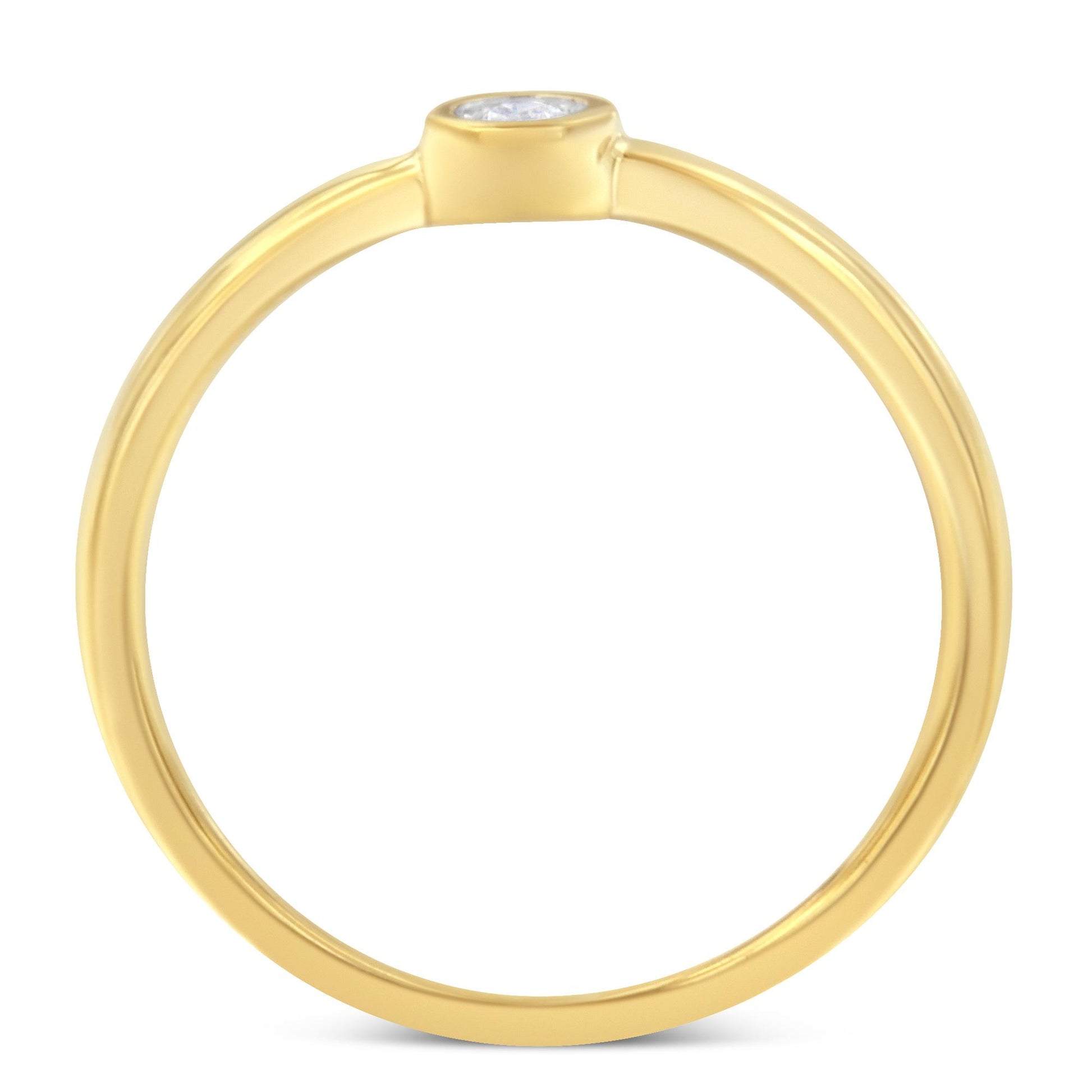 Top-down close-up of a yellow ring with a single round white gemstone in a bezel setting.