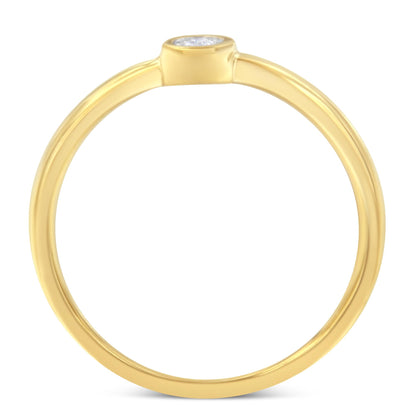 Top-down close-up of a yellow ring with a single round white gemstone in a bezel setting.