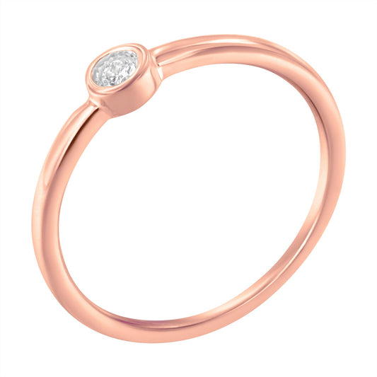 Rose metal ring with a round white gemstone in a bezel setting, shown in close-up angled view.