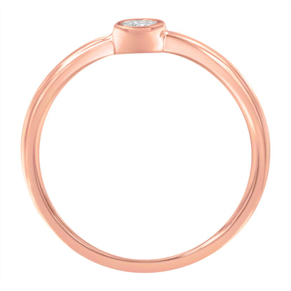 Close-up side view of a rose-colored ring with a single round white gemstone set in a bezel setting.