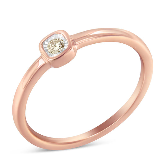 Rose-colored ring with a round white gemstone in a miracle setting, shown at an angled close-up.
