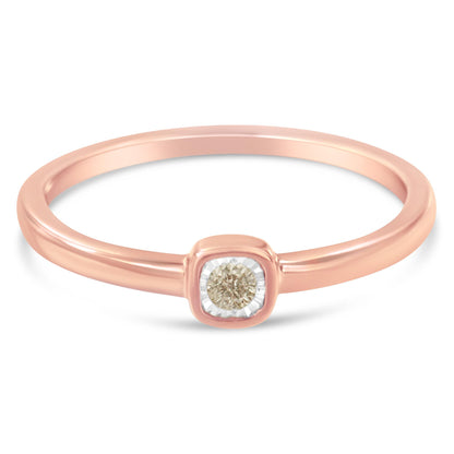 Close-up front angle of a rose-colored ring with a single round white gemstone in a miracle setting.