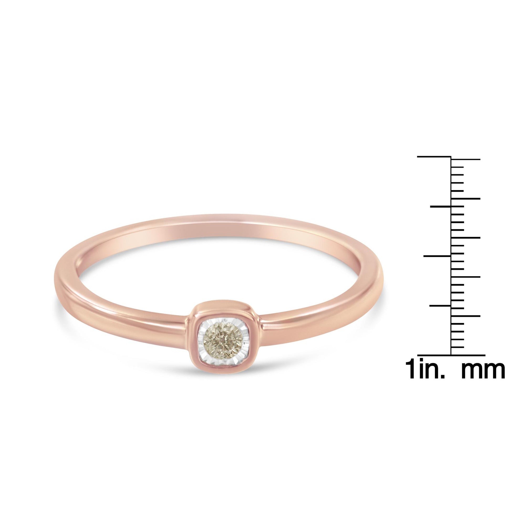 Rose metal ring with single round white gemstone in a miracle setting, shown from a front angle with a ruler for size reference.